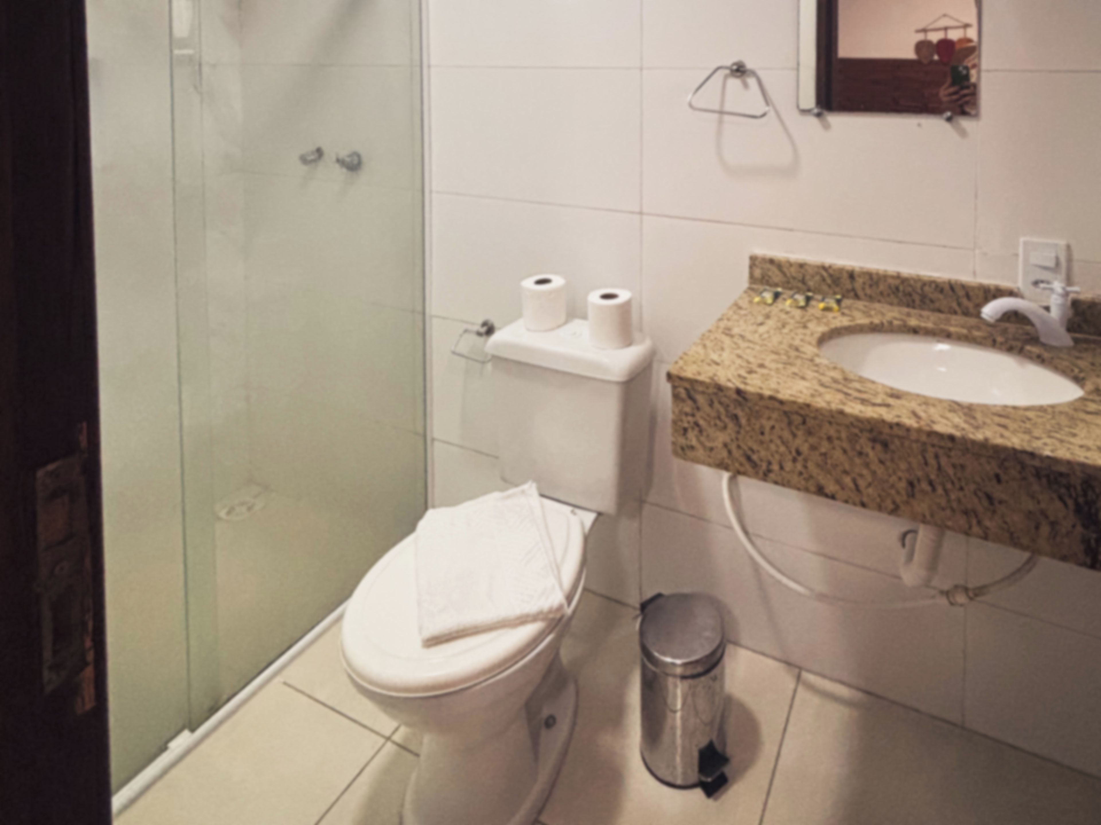 Un baño con inodoro, lavamanos y cubo de basura.