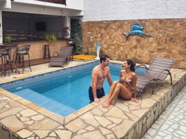 A swimming pool with lounge chairs and a stone wall.