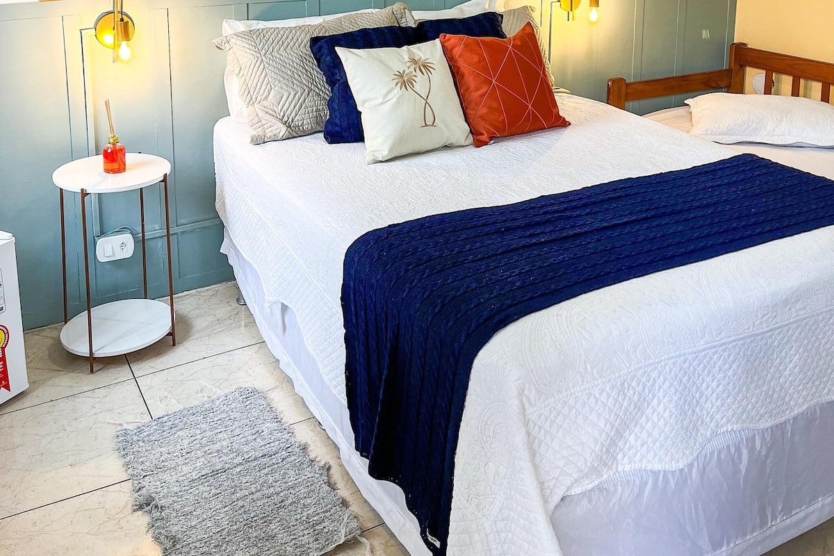 A bedroom with a large bed, a curved wall with woven decorations, a small round table with a candle, and two wall-mounted lamps.