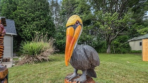 A large bird sculpture on a wooden base in a garden setting.