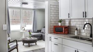 A modern kitchen with white cabinets, a red microwave, and a sink.