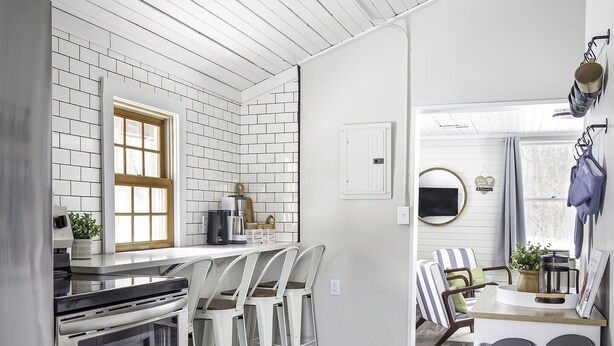 A modern kitchen with white subway tiles, stainless steel appliances, and a wooden ceiling.