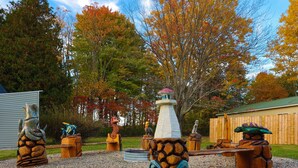 A wooden sculpture garden with various animal figures and a lighthouse.