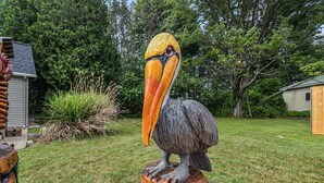 Eine große Vogel-Skulptur auf einem Holzfuß in einem Garten.