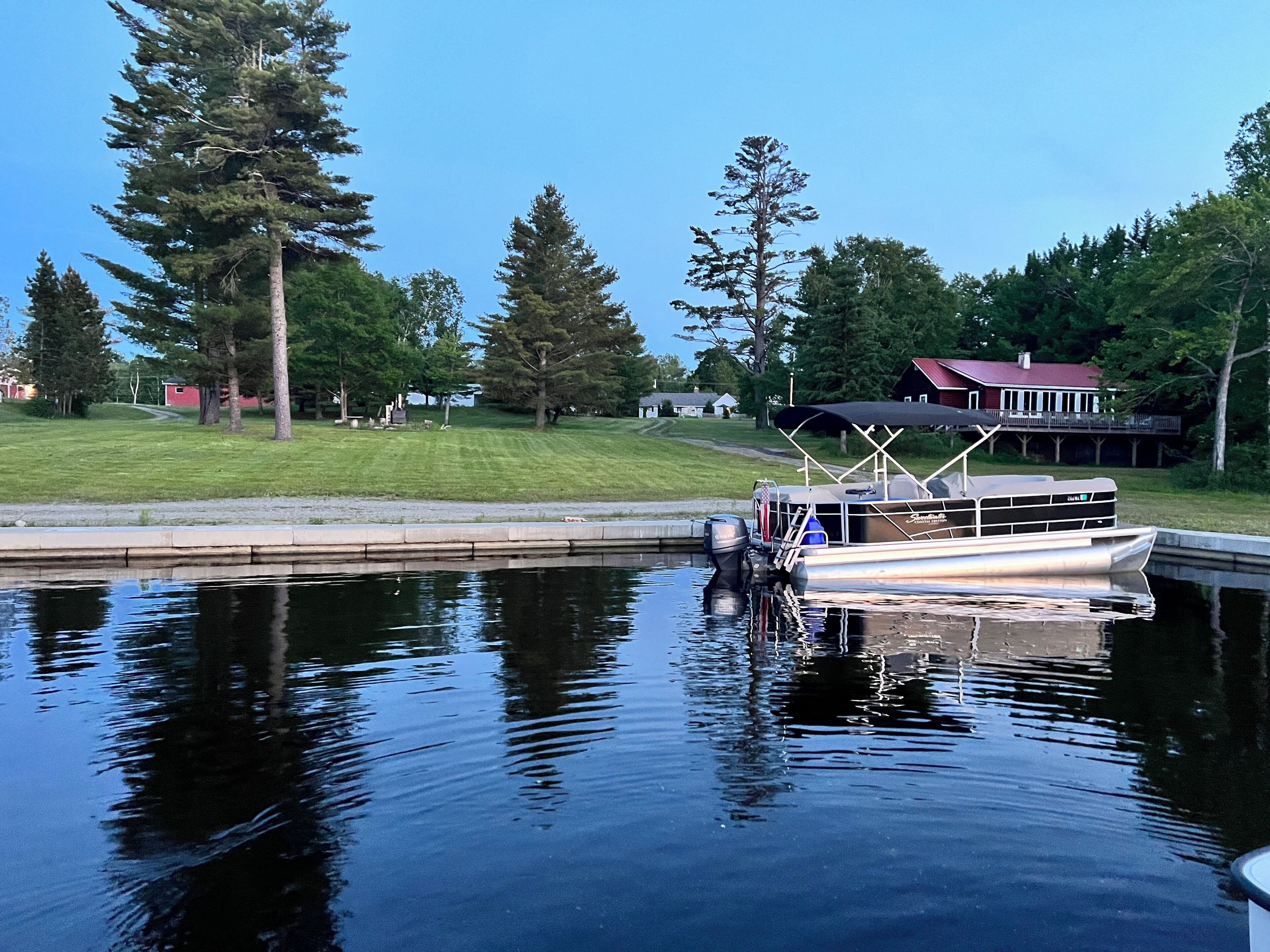 A boat docked at a calm water body with a house in the background.