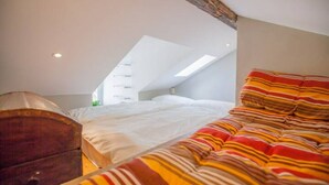 A bedroom with a sloped ceiling, a bed with striped bedding, and a wooden dresser. - GuestHost - Mansardina in Corso Como in Milan, adjacent Brera (Milano)