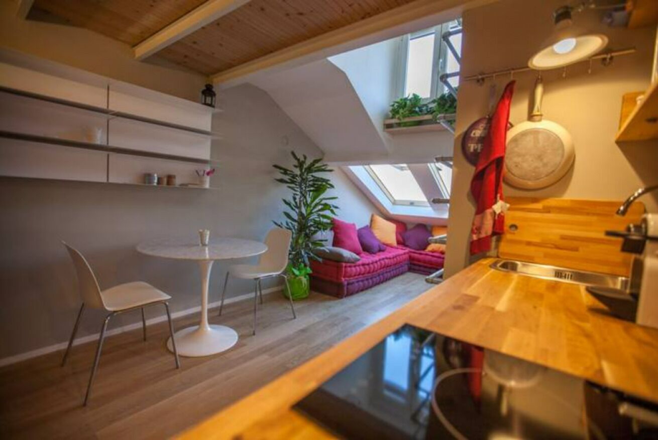 Una cucina moderna con un lucernario, una zona pranzo con un tavolo e sedie rotonde, e un angolo salotto accogliente con un divano.