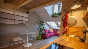A modern kitchen with a skylight, a dining area with a round table and chairs, and a cozy seating area with a sofa. - GuestHost - Mansardina in Corso Como in Milan, adjacent Brera (Milano)