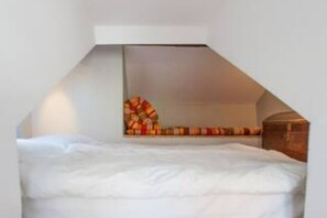 Une chambre à coucher avec un lit, une tête de lit en bois et un mur décoré d’un motif.