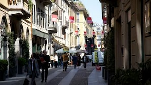 A pedestrian street lined with multi-story buildings, some with balconies and signage.
