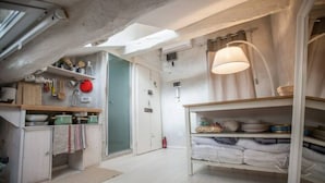 A compact kitchen with wooden cabinets, a hanging pot rack, and a ceiling skylight.