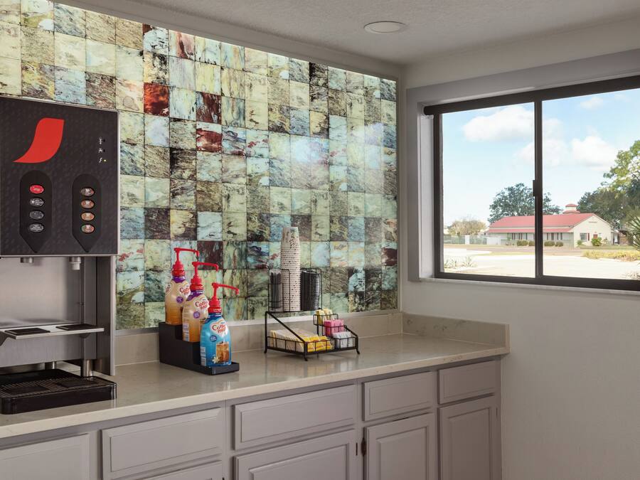 A kitchen with a coffee machine, coffee dispensers, and a window with a view of a building.