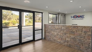 A reception area with a stone wall, a reception desk, and a view of the parking lot. - Home Inn & Suites Orlando-Apopka (Apopka)