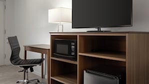 A hotel room with a flat-screen TV, a microwave, a refrigerator, a desk, and a chair. - Home Inn & Suites Orlando-Apopka (Apopka)
