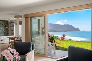 A modern living room with a large sliding glass door leading to a balcony with a view of the ocean and mountains. -  NEWLY RENOVATED! PRIME MAJESTIC OCEAN &MOUNTAIN VIEWS  OF KAUAI'S NORTH SHORE (Princeville)