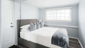 A bedroom with a bed, a window, and a door.