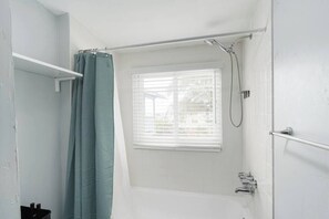 Bathtub, hair dryer, towels, shampoo