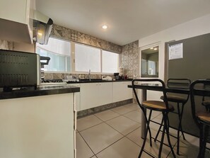 A kitchen with a central island, bar stools, and a window.