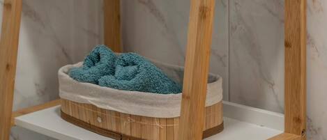 Un estante de madera con una toalla azul en una cesta, un marco de madera y un letrero azul con ilustraciones.