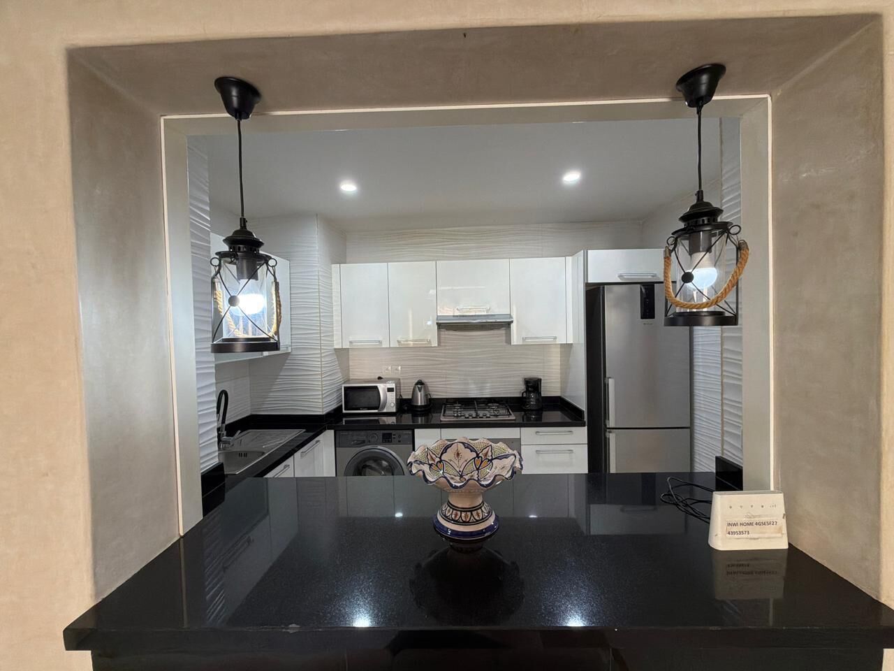 A modern kitchen with black countertops, white cabinets, and two pendant lights.