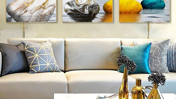 A living room with a sofa, decorative pillows, and three framed artworks on the wall. - Superb apartment at the marina (Agadir)