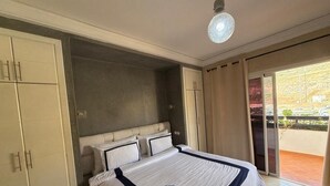 A hotel room with a large bed, a wardrobe, and a sliding glass door to the outside. - Superb apartment at the marina (Agadir)