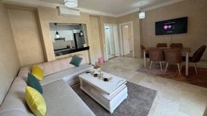 A living room with a sofa, coffee table, and dining area. - Superb apartment at the marina (Agadir)