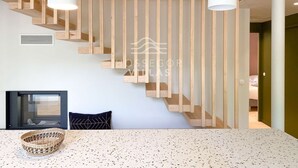 A modern interior with a staircase, a dining area, and a view into another room.