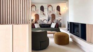 A modern living room with a sofa, ottoman, and a fireplace.