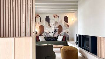 Een moderne woonkamer met een bank, voetenbankje en een open haard.