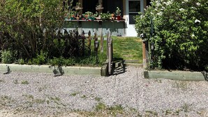 Una casa con porche, rodeada de árboles y un camino de grava.