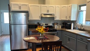 Una cocina moderna con gabinetes blancos, electrodomésticos de acero inoxidable y una mesa redonda con sillas.