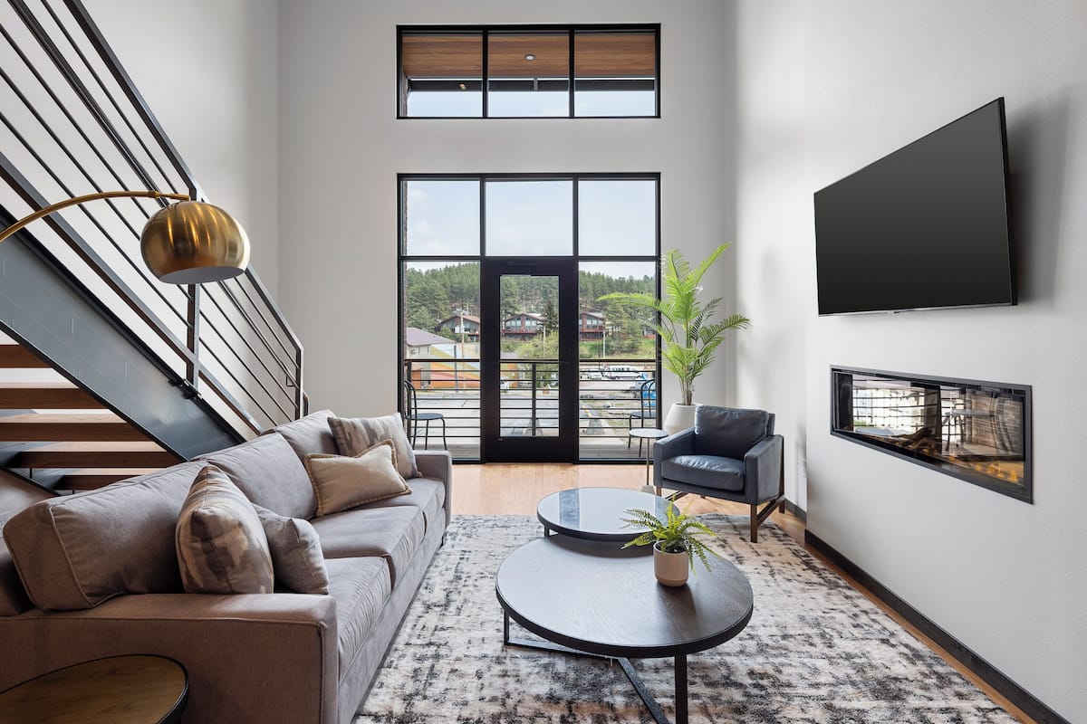 Un salon moderne avec un canapé, une table basse et un téléviseur à écran plat fixé au mur.