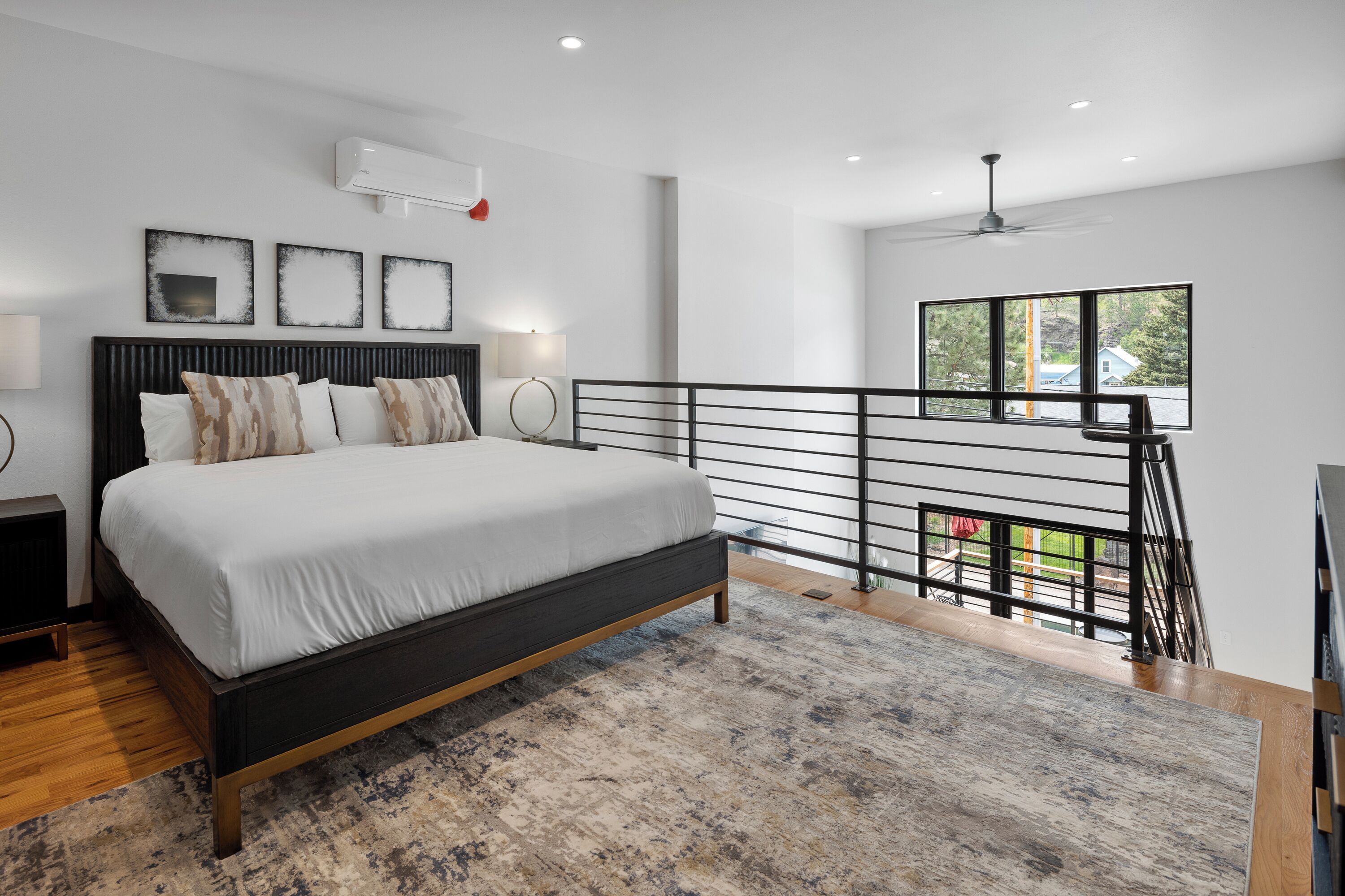 Una camera da letto moderna con un grande letto, un balcone con ringhiera e vista sull'esterno.