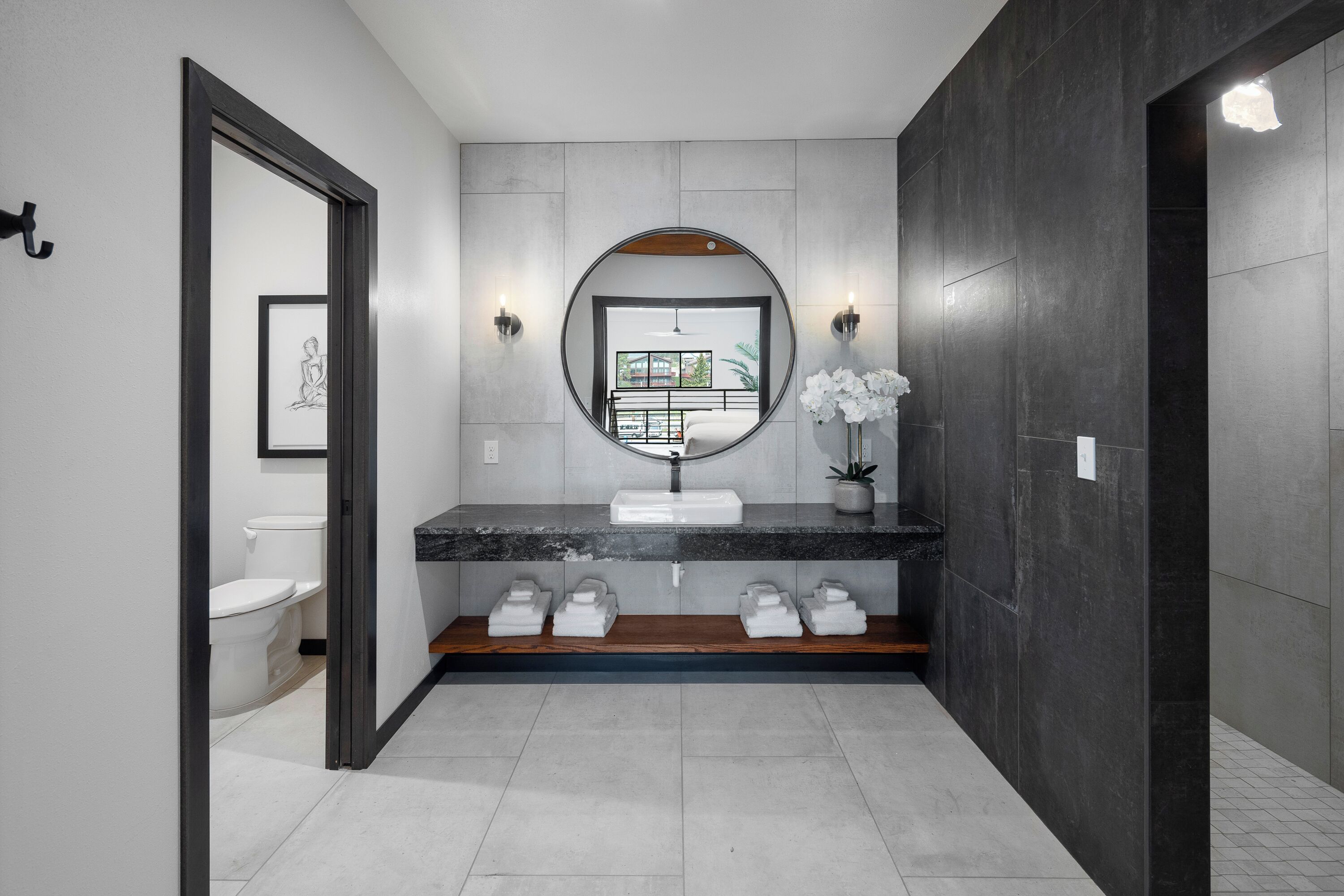 Un baño moderno con un espejo grande, un lavamanos redondo y vistas a un balcón.