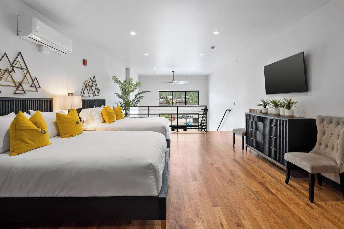 Une chambre d’hôtel moderne avec deux lits, une télévision, un balcon et une vue sur la ville.