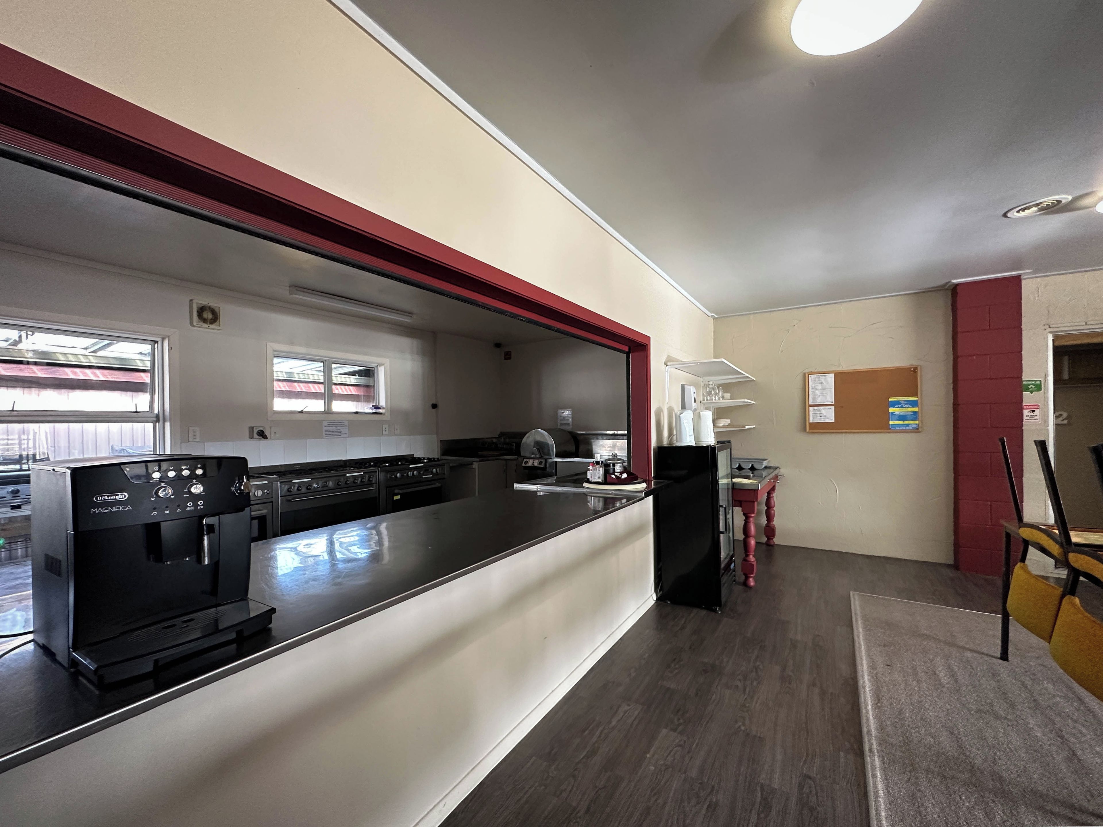 A commercial kitchen with stainless steel appliances, a coffee machine, and a service counter.