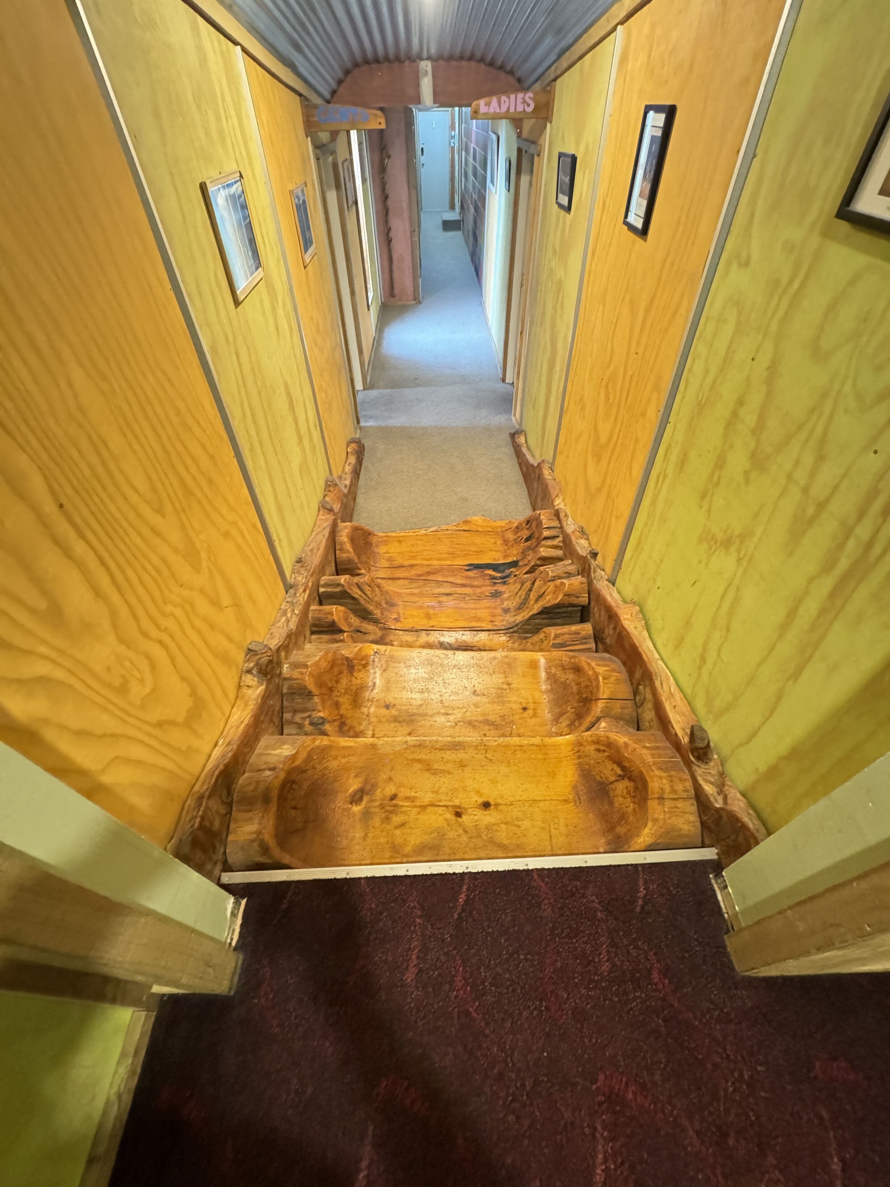 A wooden interior hallway with a central wooden bench.