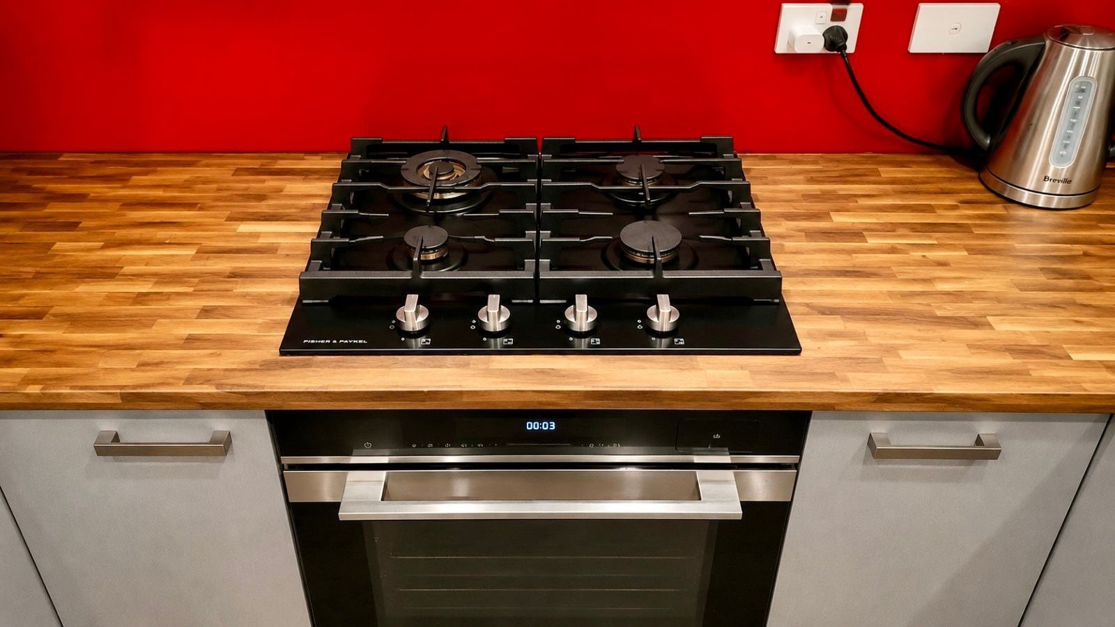 A kitchen with a black stove, a stainless steel oven, and a Breville kettle.