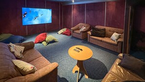 Tunnelmallinen olohuone, jossa on kaksi sohvaa, pieni sohvapöytä ja televisioruutu, jossa näkyy lentäviä lintuja.
