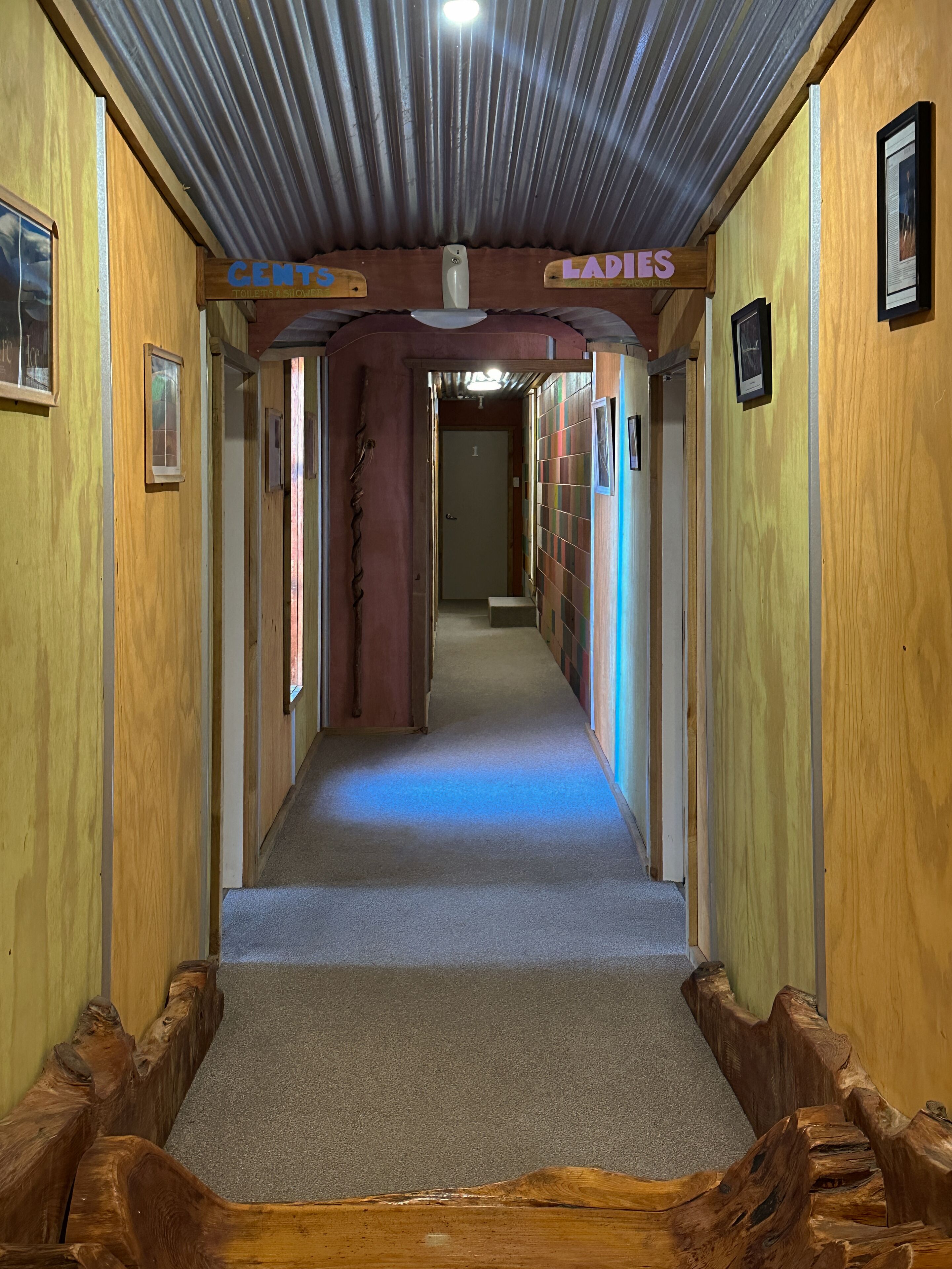 Un pasillo con paredes de madera, suelo alfombrado y un banco de madera al final.