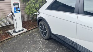 Un SUV blanco estacionado en una estación de carga para vehículos eléctricos.