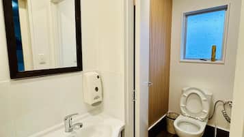 Un baño moderno con lavamanos, espejo y retrete blancos.
