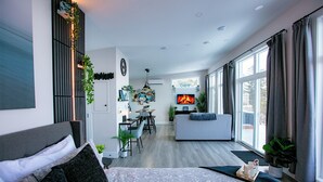 Una sala de estar moderna con sofá, comedor y televisión mostrando una chimenea.