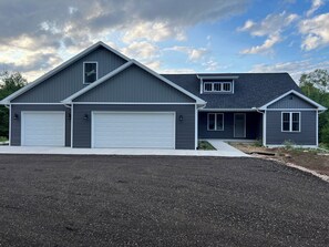 A modern two-story house with a garage, a covered patio, and a landscaped driveway.