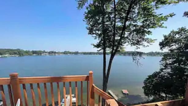 Una terraza de madera con vista a un lago tranquilo y un cielo despejado.