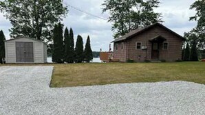 Una casa con camino de grava y un cobertizo pequeño.