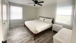 A bedroom with a bed, bedside tables, a ceiling fan, and a window with blinds. - OCNJ Newly Renovated 4BR! (Ocean City)