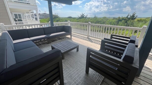 A covered outdoor deck with a sofa, chairs, and a table. - OCNJ Newly Renovated 4BR! (Ocean City)