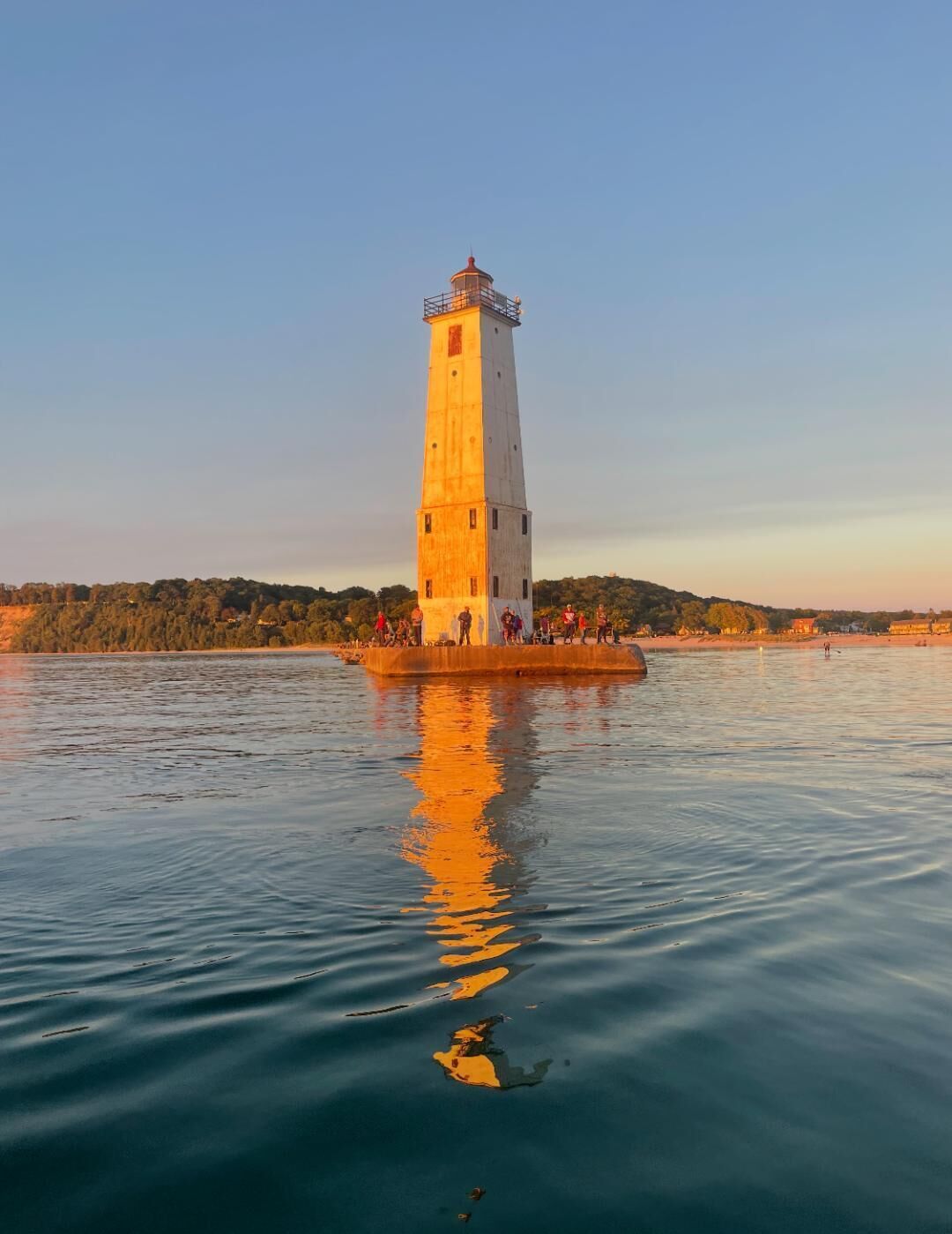 A lighthouse on a small island with calm water reflecting its structure.